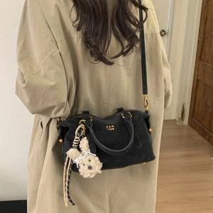 Détail du sac Boston en daim noir avec lettrage doré et pendentif lapin en peluche