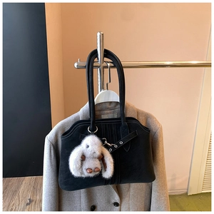 Detail of black matte tote bag with metallic buckle strap and a plush rabbit pendant