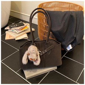 Detail view of dark brown suede tote with decorative strap and rabbit plush charm