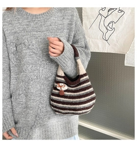 Close-up of knit tote bag with brown stripes and a 3D mushroom charm decoration