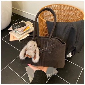 Detail of vintage brown suede tote bag with tie-strap design and plush rabbit charm
