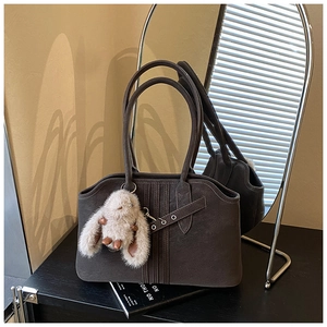 Close-up of vintage suede tote bag with vertical stitching and cute rabbit plush charm