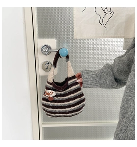Close-up of striped knit tote bag with mushroom patch hanging on a door handle