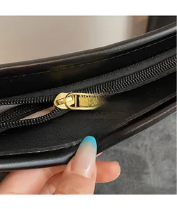 Close-up of golden zipper pull with SOUKU engraving on smooth black leather tote bag
