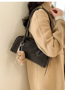 Détail d'un sac seau vintage marron foncé avec surpiqûres contrastées et breloque chien