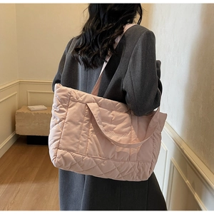 Detail of light pink quilted nylon tote bag featuring elegant cursive embroidery