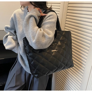 Détail du sac cabas matelassé en similicuir noir avec logo métallique et motif à losanges chic