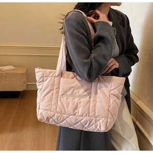 Detailed view of pink quilted tote bag with diamond stitching and elegant cursive embroidery