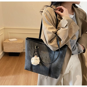 Close-up of dark grey marble texture tote bag with a white plush lamb keychain charm