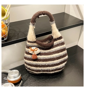 Macro shot of striped knit bucket bag with small mushroom charm on monochrome stairs