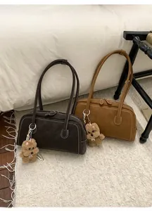 Détail de sacs Boston vintage avec coutures contrastées et breloques chien en peluche