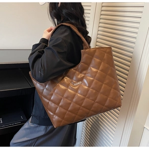 Détail d'un sac cabas marron matelassé avec plaque métallique et texture en cuir