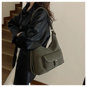 Detail of dark green vintage tote bag with buckle pocket on a black leather coat