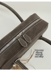Détails des fermetures éclair doubles et coutures blanches sur sac cuir marron