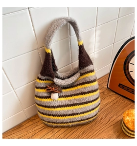 Detail of handmade knit hobo bag with colorful stripes and a 3D mushroom charm