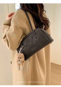 Detail of dark grey retro bowling bag with white stitching and plush dog charm