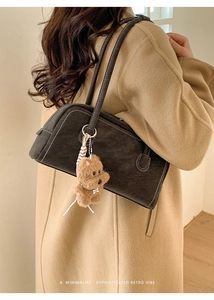 Detail of dark brown retro bowling bag with contrast stitching and plush puppy charm