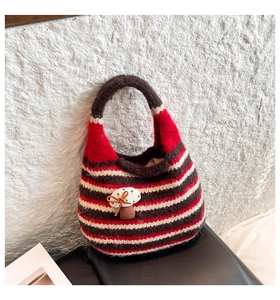 Detail view of the hand-knitted striped bucket bag with a cute mushroom patch decoration