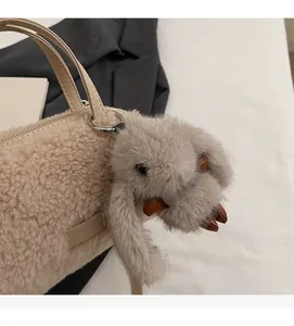 Nahaufnahme der beigen Kunstpelz-Handtasche mit süßem Plüschhasen-Anhänger und Lederetikett