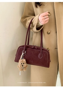 Burgundy bowling bag with white stitching detail and a cute plush dog pendant charm
