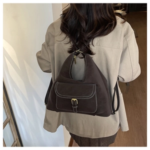 Close-up of vintage brown backpack with flap pocket, metal buckle, and contrast stitching