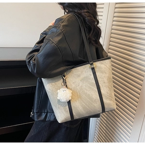 Detail of grey marble textured tote bag with black shoulder strap and plush charm