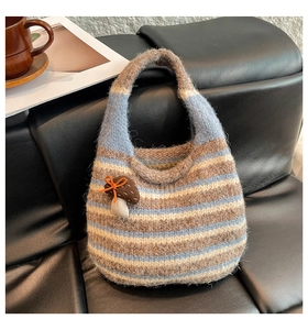 Close-up of a striped knit tote bag with a cute mushroom charm on a black leather sofa