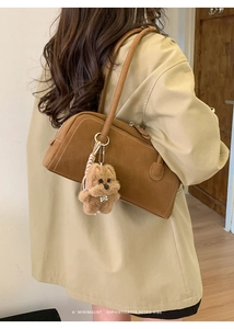 Brown retro bowling bag with plush bear charm worn by model for an elegant minimal look