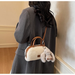 Detail der flauschigen weißen Teddy-Tasche mit braunem Lederbesatz und Hasen-Anhänger