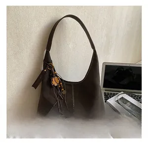 Macro shot of dark brown suede hobo bag with white stitching and wood flower charm