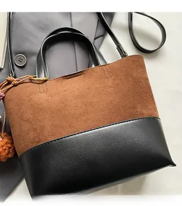 Close-up of contrast brown suede and black leather stitching on a bucket tote bag