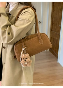 Detail of retro brown suede bowling bag with logo and cute puppy pendant on shoulder