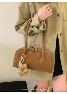 Gros plan du sac bowling vintage en daim marron avec logo embossé et breloque ourson