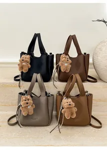 Detailed view of four textured leather bucket bags with plush bear charms and straps