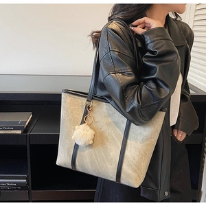 Close-up of marble textured tote bag with black leather straps and a sheep charm