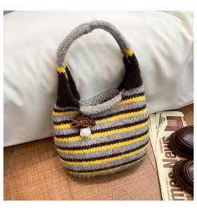 Detail of striped knitted handbag featuring a 3D mushroom charm and warm cozy texture