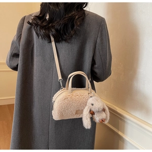 Detail der flauschigen cremefarbenen Lammwoll-Tasche mit süßem Hasenanhänger