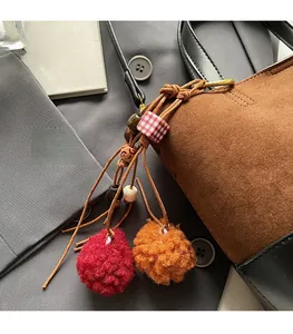Detail of red and orange faux fur pompom bag charm with retro beads on a brown handbag