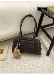 Gros plan du sac bowling rétro avec coutures contrastées et breloque chien en peluche