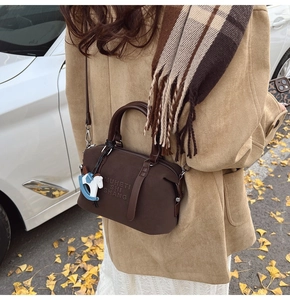 Dettaglio della borsa Boston in pelle marrone con goffratura MUHETI SHISHANG e ciondolo