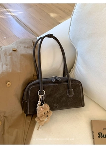 Detail of vintage brown bowling bag with contrast stitching and teddy bear charm