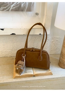 Detailed view of a brown vintage bowling bag with white stitching and bear charm