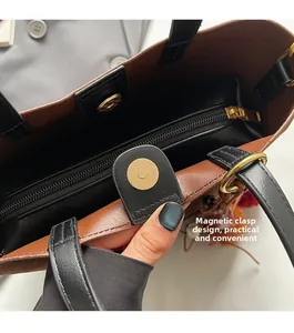 Detail of color-block bucket bag with magnetic closure and golden hardware zipper pocket