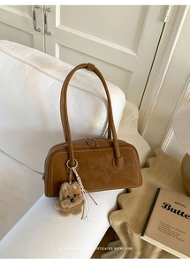 Brown retro leather bowling bag with contrast stitching and plush teddy charm detail