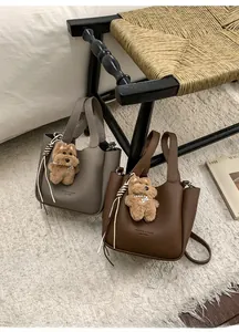 Detail of lychee textured bucket bags with cute plush dog pendants and brand logo
