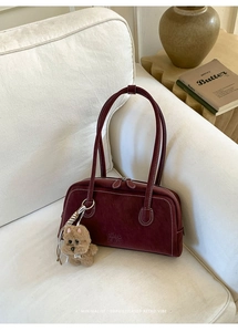 Detail of dark red vintage bowling bag with contrast stitching and plush dog charm
