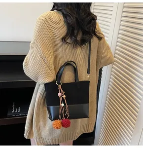 Detail of black patchwork bucket bag with colorful tassel charm in interior setting