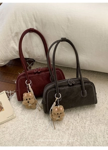 Detail of burgundy and grey bowling bags with contrast stitching and plush dog charms