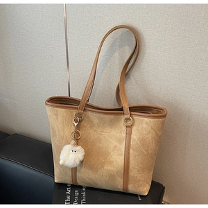 Close-up of khaki faux suede tote bag with delicate embossing and plush charm detail