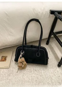 Close-up of black matte bowling bag featuring white stitching and a plush puppy charm